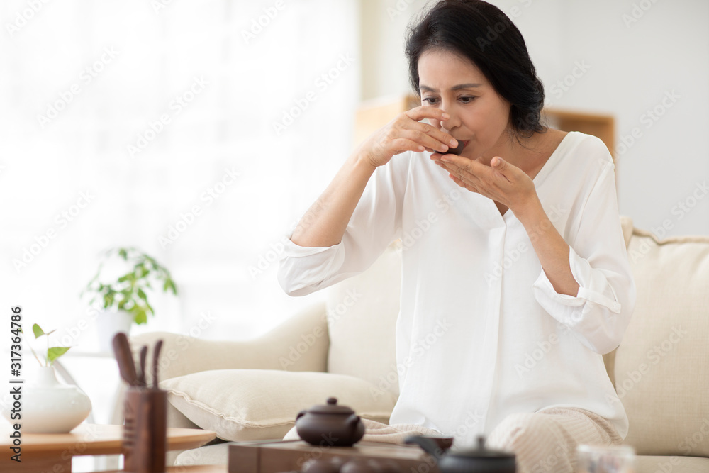 Mature woman drinking tea in living room Mature woman drinking tea in living room