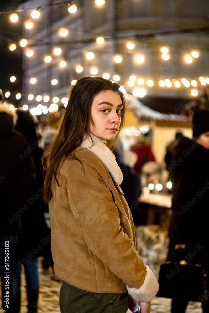 girl in a christmas park looking at the camera. garland background. bright lights