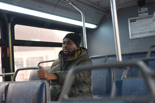 African American man on a bus, going to work in the morning. Everyday man commuting to work by public transport. Handsome man traveling to work. 