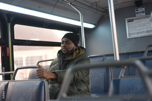 African American man on a bus, going to work in the morning. Everyday man commuting to work by public transport. Handsome man traveling to work. 