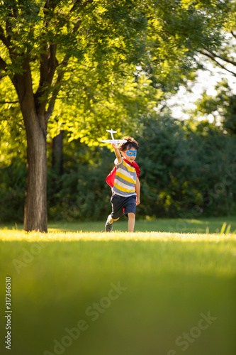 Little boy in superman costume playing on meadow