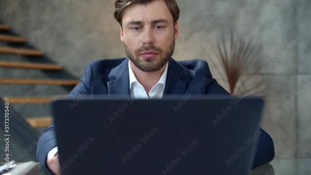 Focused businessman working on laptop in office. Top manager reading text.