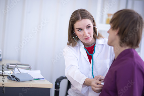 Portrait Of Female Doctor Wearing White Coat  with stethoscope, is Examining male Patient in the hospital. photo