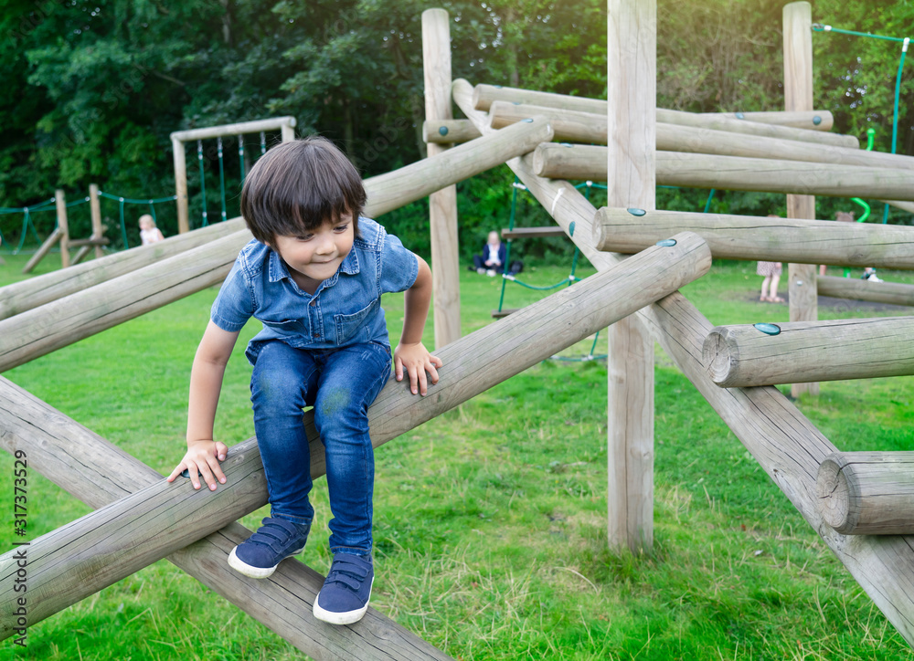 Portrait kid climbing on wooden fame in the park, Child enjoying activity in a climbing adventure park on summer sunny day, little boy having fun in playground. Portrait kid climbing on wooden fame in the park, Child enjoying activity in a climbing adventure park on summer sunny day, little boy having fun in playground.