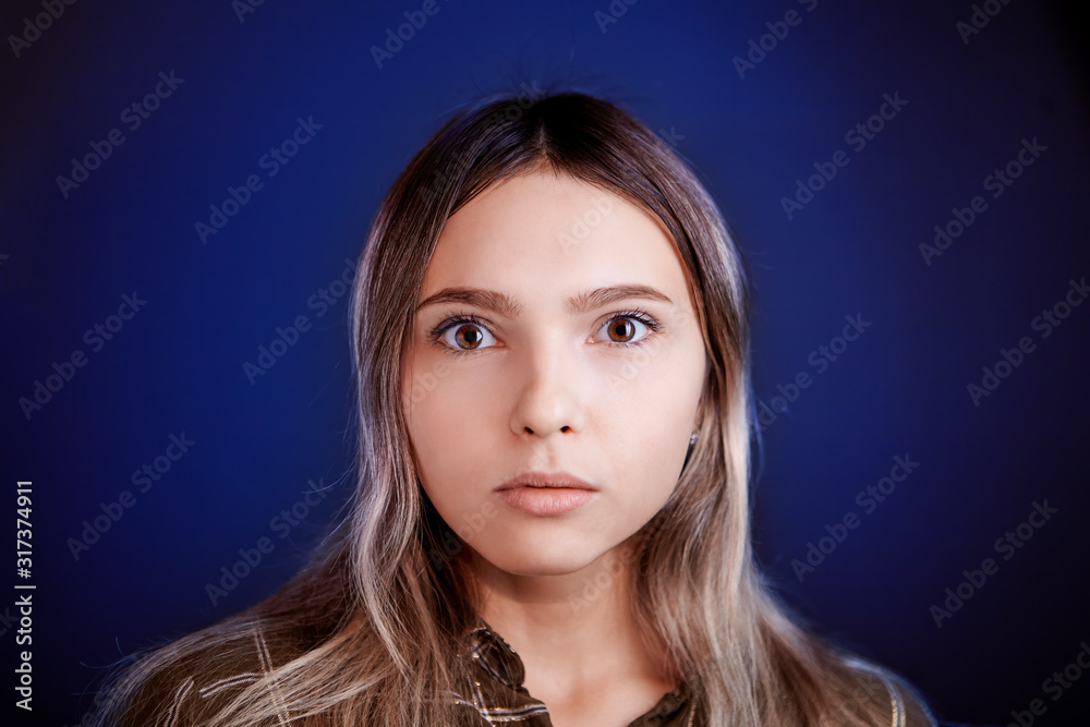 Naklejka premium Young woman with wide eyes on a blue background.