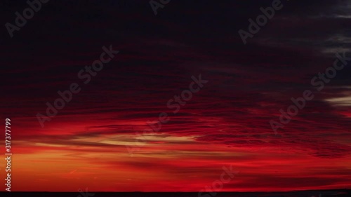 Time lapse of a vibrant red and orange sky as the clouds light up with color during sunset. Over a beach on Long Island New York.  photo
