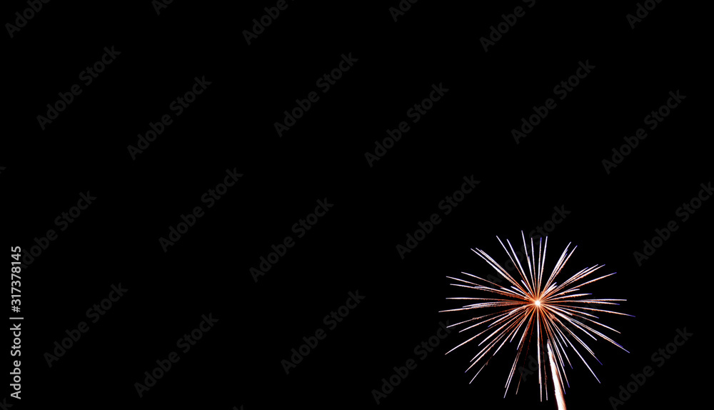 Small white starburst firework in lower right hand corner with black background Small white starburst firework in lower right hand corner with black background