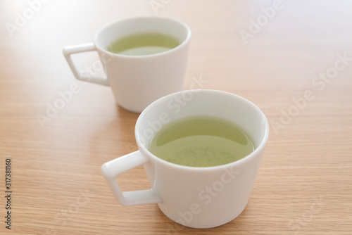 シンプルなマグカップに入れた緑茶 ２つ 2人 ２人 ふたり 二人 余白 ホワイトスペース 文字スペース コピースペース 空白 背景 背景素材 グラフィック背景 グラフィック素材 木目 木 テーブル 机 上