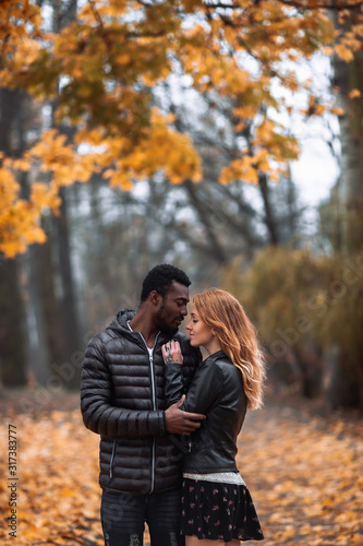 Interracial couple posing in blurry autumn park background