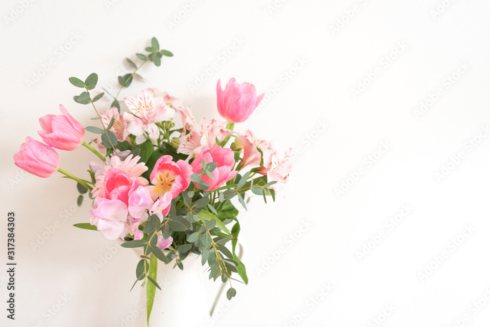 シンプルな花瓶とピンク系の花　ピンク系の花とグリーン　花瓶　白い花瓶　　部屋　白壁　白背景　室内　屋内　自然光　余白　ホワイトスペース　コピースペース　文字スペース　縦　背景素材　背景　グラフィック素材　　白　緑　ピンク　春　季節　スイートピー