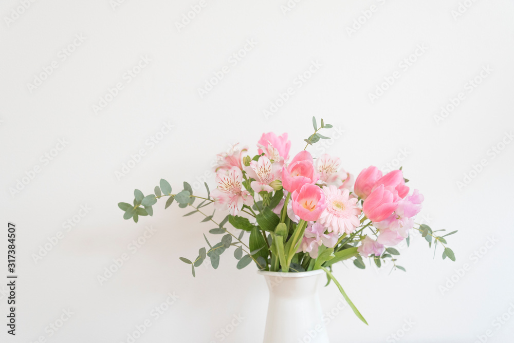 白い花瓶とピンク系の花　おしゃれ　アレンジ　春　季節　部屋　白い壁　白背景　テーブル　フラワーアレンジメント　インテリア写真　春の花　花器　家　白バック　花瓶　　縦