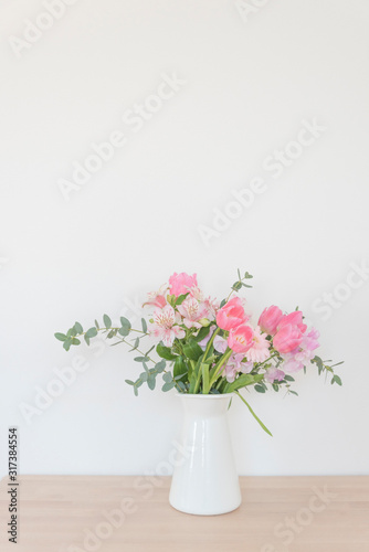 白い花瓶とピンク系の花　おしゃれ　アレンジ　春　季節　部屋　白い壁　白背景　テーブル　フラワーアレンジメント　インテリア写真　春の花　花器　家　白バック　花瓶　　縦
