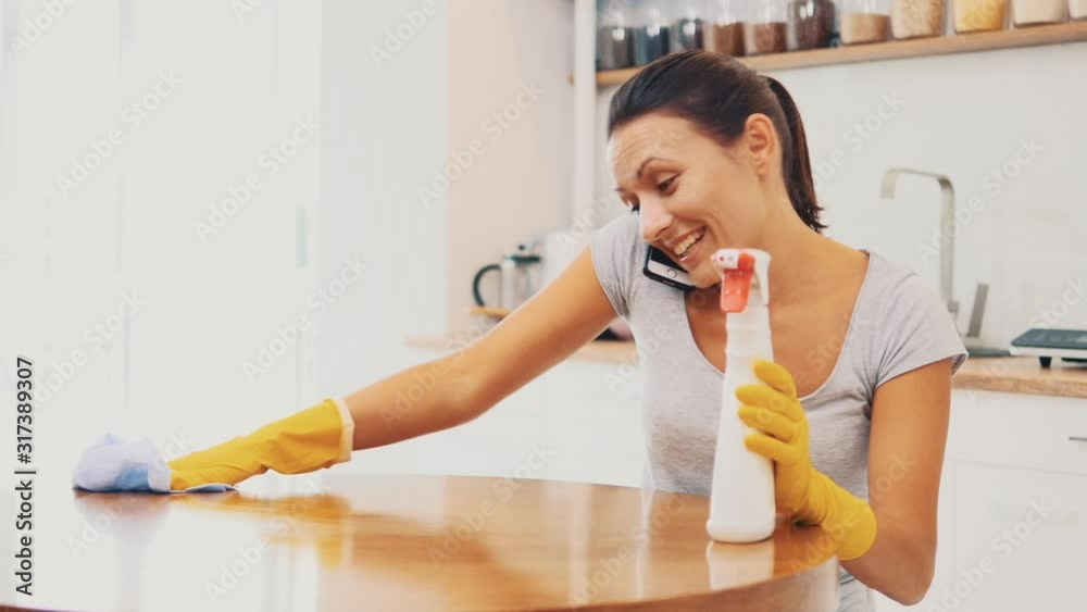 Woman in yellow rubber gloves is cleaning cooking panel in kitchen with fat remover spray and a cloth. Crop. Copy space. Close up. 4K. Woman in yellow rubber gloves is cleaning cooking panel in kitchen with fat remover spray and a cloth. Crop. Copy space. Close up. 4K.