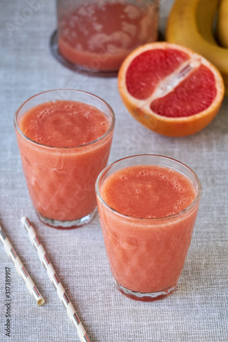 Two glasses of grapefruit smoothie on a gray background 