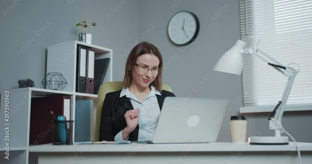 Young Beautiful Brunette Works on a Laptop Computer in Cool Creative Agency in a Loft Office. She has a Take-away Coffee and a Notebook on Her Table Young Beautiful Brunette Works on a Laptop Computer in Cool Creative Agency in a Loft Office. She has a Take-away Coffee and a Notebook on Her Table