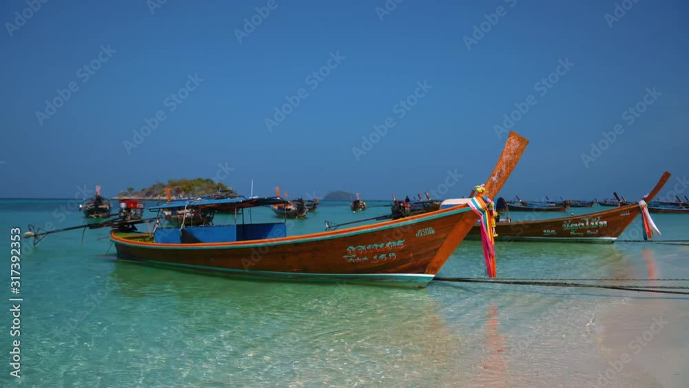 Famous and iconic Thai longtail boats on an empty sandy beach on the remote island Koh Lipe in Thailand, close to the Malaysian border. The water is turquoise and clear like in paradise. Famous and iconic Thai longtail boats on an empty sandy beach on the remote island Koh Lipe in Thailand, close to the Malaysian border. The water is turquoise and clear like in paradise.