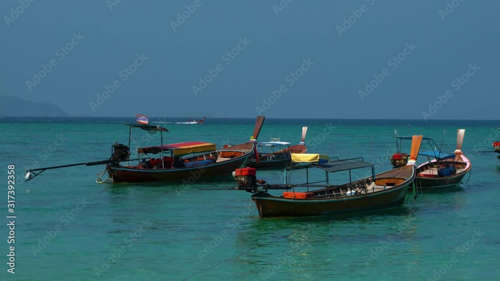 Traditional and iconic Thai longtail boats on an empty sandy beach on the remote island Koh Lipe in Thailand, close to the Malaysian border. The water is turquoise and clear like in paradise. Traditional and iconic Thai longtail boats on an empty sandy beach on the remote island Koh Lipe in Thailand, close to the Malaysian border. The water is turquoise and clear like in paradise.