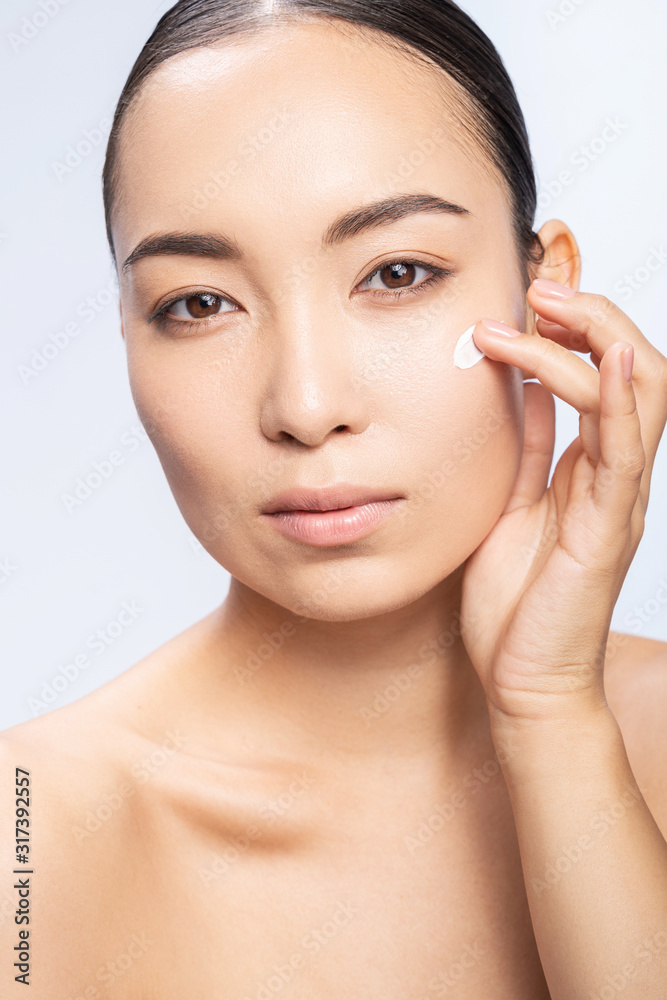 Beautiful young woman takes care of her face in studio