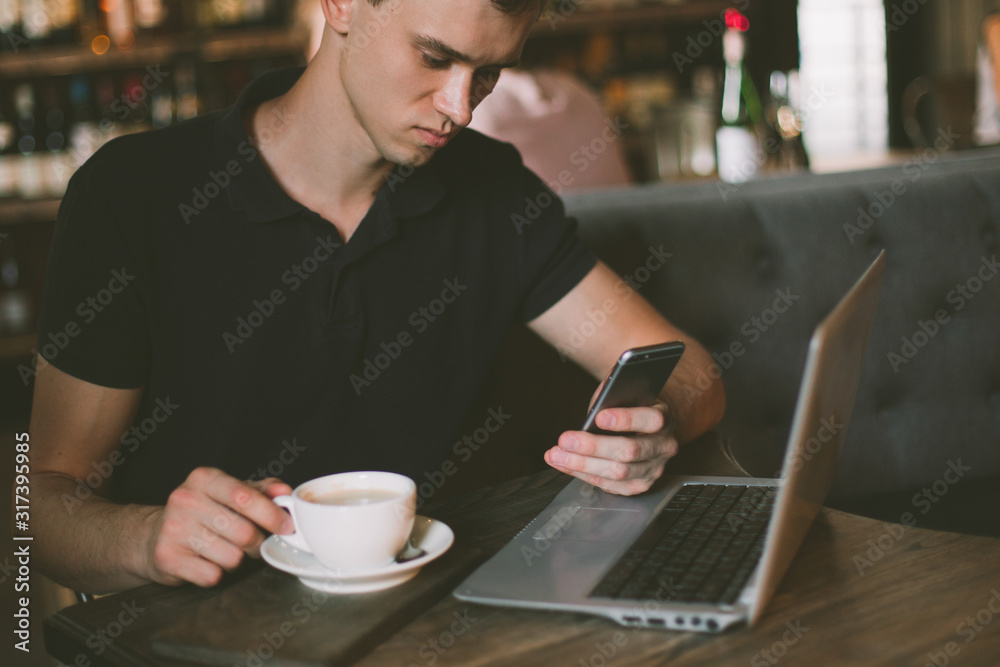Businessman working on a laptop and using phone in a cafe.