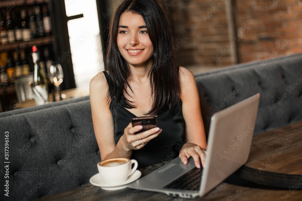 Business woman working on a laptop, using phone and drinking coffee in a cafe. Business woman working on a laptop, using phone and drinking coffee in a cafe.