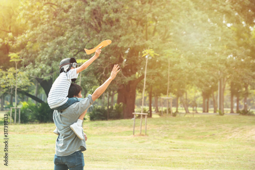Asian father and son play with paper plane in public park in summer , fatherhood and kid have leisure activity together. © mkitina4
