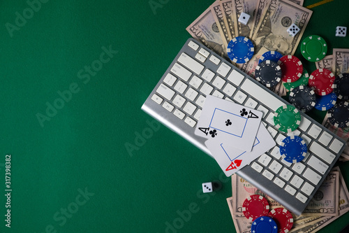Online poker. Chips and the dice nearby keyboard on green table top view copyspace