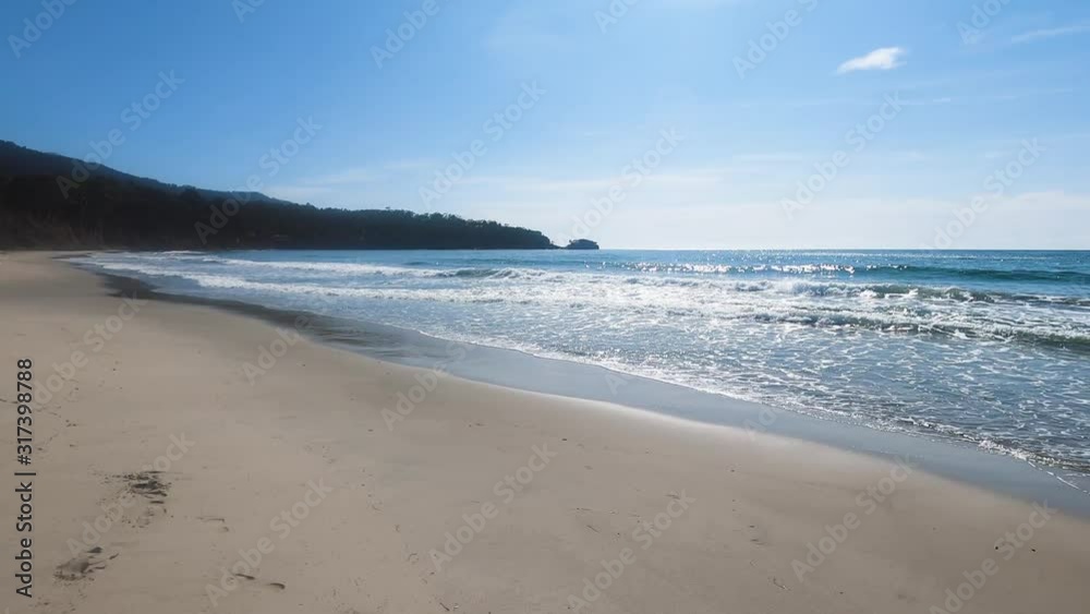 view of the beach next to the Tessalated Pavement in Eaglehack Neck in the Tasman Peninsula in Tasmania with the ocean glimmering from the sunshine view of the beach next to the Tessalated Pavement in Eaglehack Neck in the Tasman Peninsula in Tasmania with the ocean glimmering from the sunshine