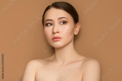 beautiful fashion woman. Portrait with natural make-up on a beige background.