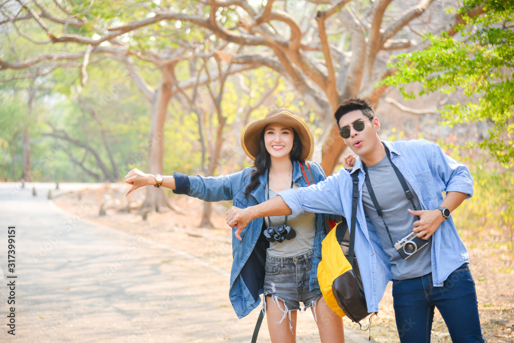 Young asian couple doing hitchhike hand on the street in park. Young asian couple doing hitchhike hand on the street in park.