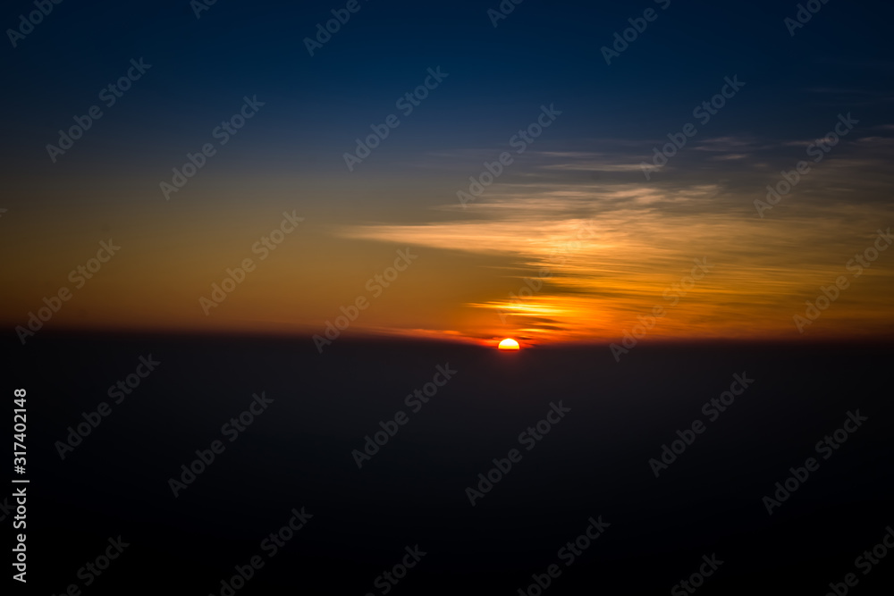 Impressive sunrise over forest and hill silhouettes with orange sky.  Amazing beautiful romantic morning and meadow scene.