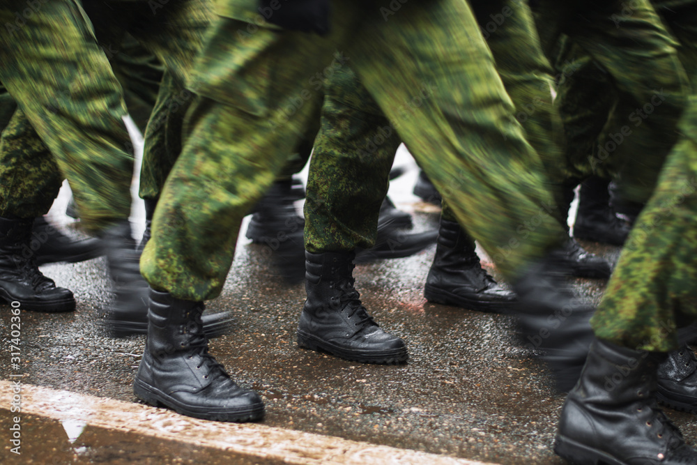 Soldier boots walking on wet asphalt during the parade of memory. The military marching down the street. Many shoes and camouflage clothing. Motion lubrication. Soldier boots walking on wet asphalt during the parade of memory. The military marching down the street. Many shoes and camouflage clothing. Motion lubrication.