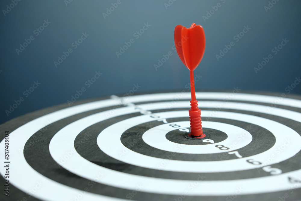Wooden dartboard with red arrow on dark background Wooden dartboard with red arrow on dark background
