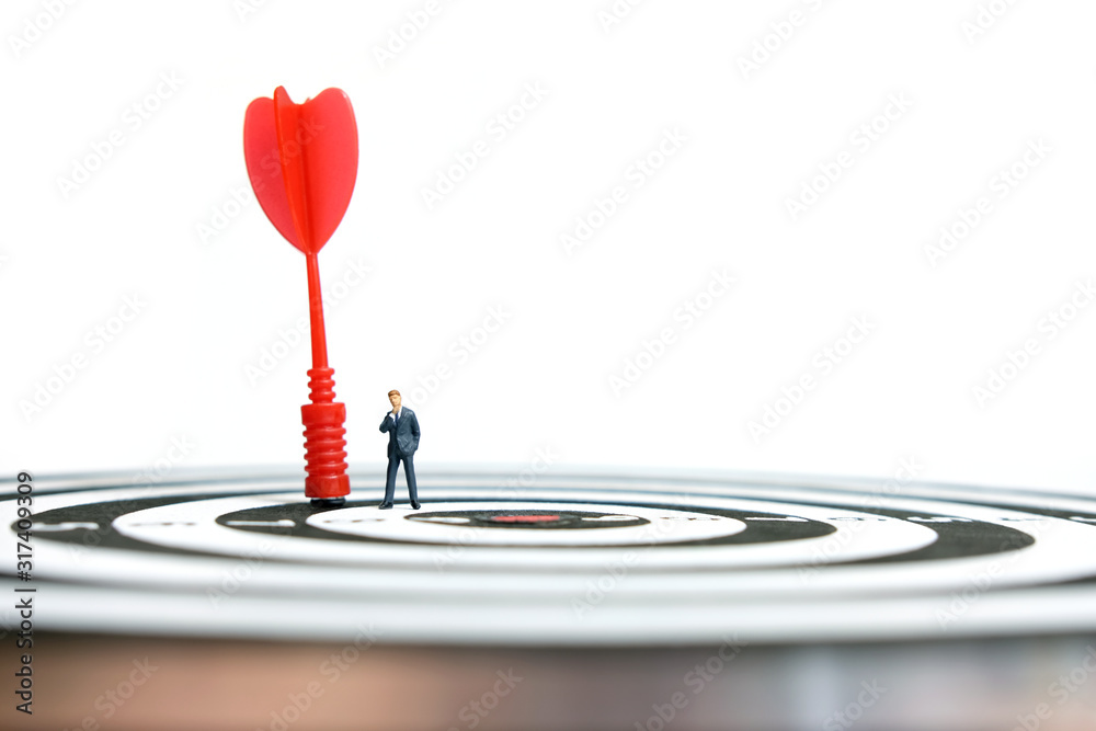 Business strategy conceptual photo - Miniature businessman with red arrow on a dartboard Business strategy conceptual photo - Miniature businessman with red arrow on a dartboard