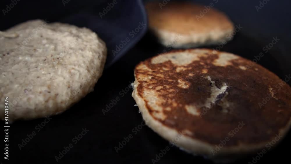 Turning half cooked pancakes with a black plastic spatula Turning half cooked pancakes with a black plastic spatula