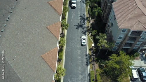 Aerial Overhead Drone View Following White Sedan Car Driving through Streets in Orlando Florida with View of Palm Trees on A Sunny Afternoon Day 4K
