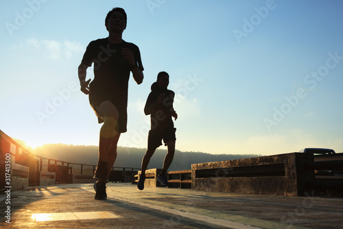 Canvas Print Two young runners are jogging in the evening.
