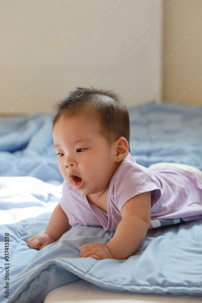 A cute baby boy yawning on blue blunket in her bed, She shows emotions, mood, soft focus A cute baby boy yawning on blue blunket in her bed, She shows emotions, mood, soft focus