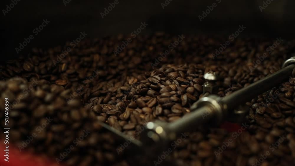 Close-up of mixing and stirred fragrant black coffee beans in roasting machine. Preparation of high quality fragrant coffee beans, closeup, no people. Shooting in slow motion. Close-up of mixing and stirred fragrant black coffee beans in roasting machine. Preparation of high quality fragrant coffee beans, closeup, no people. Shooting in slow motion.