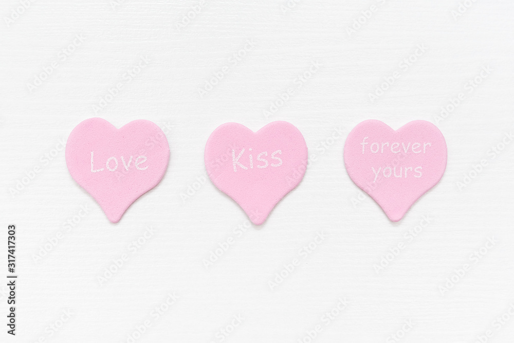 Tree pink hearts with text LOVE, KISS, FOREVER YOURS on white background with copy space. Valentines day concept. Gift for lover, love confession. Top view Flat lay Minimal style.