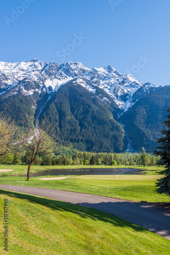 Golf course with gorgeous green and fantastic snow mountain view.