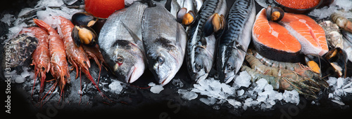 Fresh fish and seafood on black background.