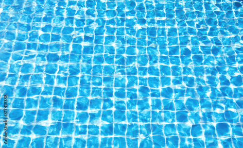 Blue water surface with bright sunlight reflections, water in swimming pool background