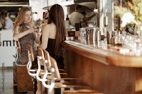 Εκτύπωση καμβά Two gorgeous young women sitting at the bar, day time