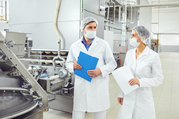 Technologists inspector in masks at food factory.