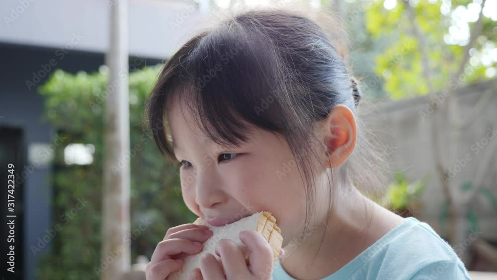 Little asian girl eating sandwich for breakfast. Little asian girl eating sandwich for breakfast.