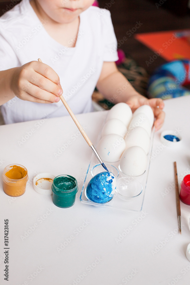 Cute little blonde boy 4 years old painting easter eggs with paint brushes. concept of kid creativity, diy, handmade. idea for kindergarten, daycare, school