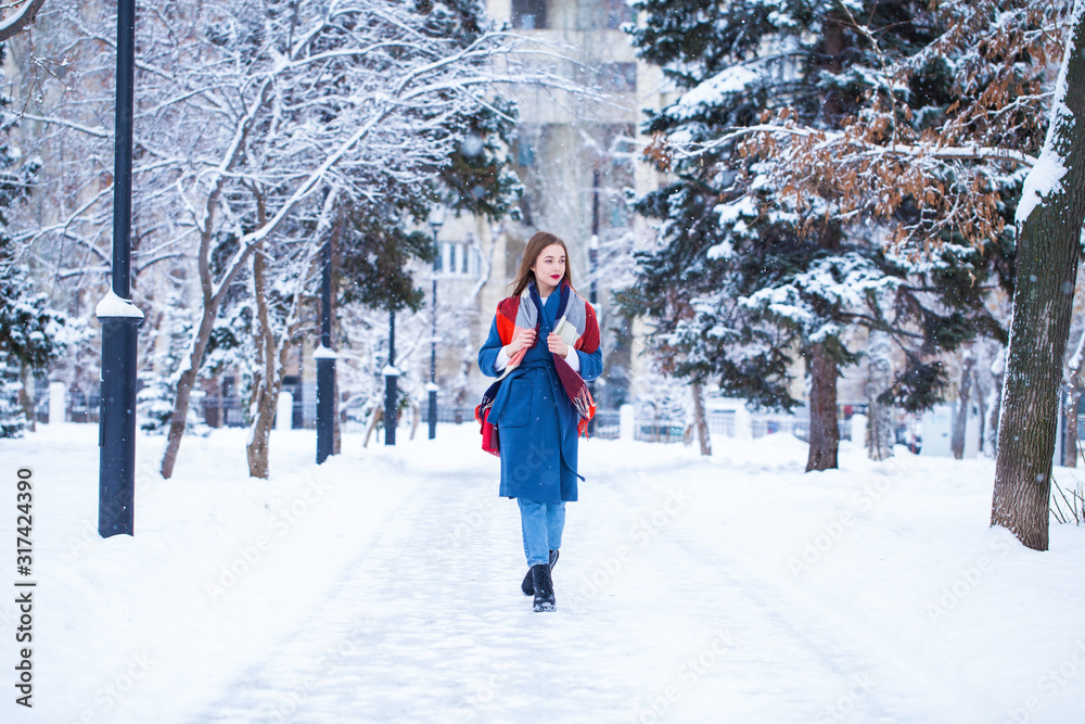 Happy young girl in blue coat posing in winter street