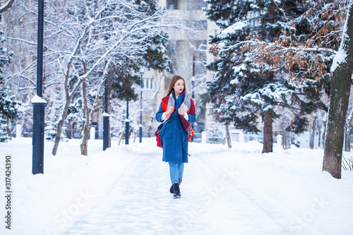 Happy young girl in blue coat posing in winter street © Andrey_Arkusha