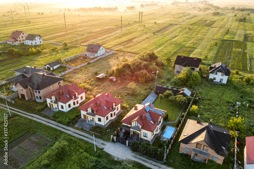 Aerial view of rural residential area with private homes between green fields at sunrise. photo