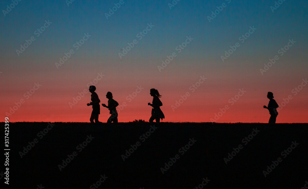 two girls running around the city marathon at sunset